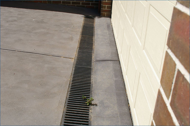 Residential photo of driveway leading to garage with specialised drainage solution.